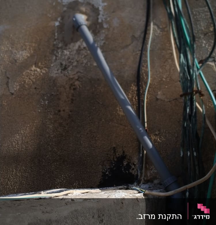 צינור פלסטיק אפור מחובר לקיר עם חוטים